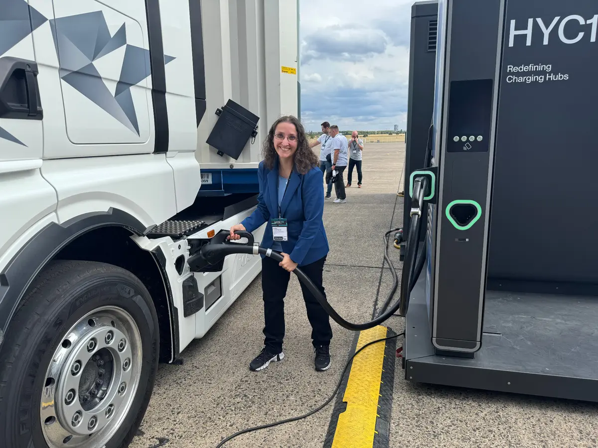 Anita Athanasas mit einem Elektro-Lkw an einer Ladestation