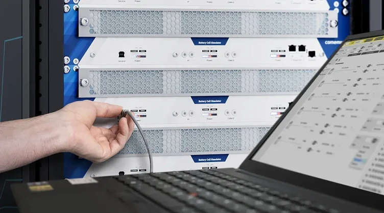 Nahaufnahme eines Ingenieurs beim Anschließen eines rackbasierten Battery Cell Simulator neben einem Laptop.