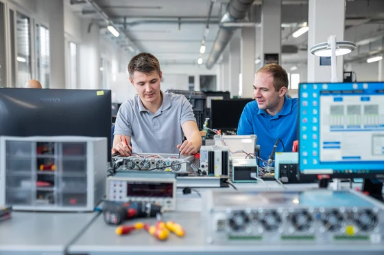 Two comemso colleagues working on an open electronic test system.