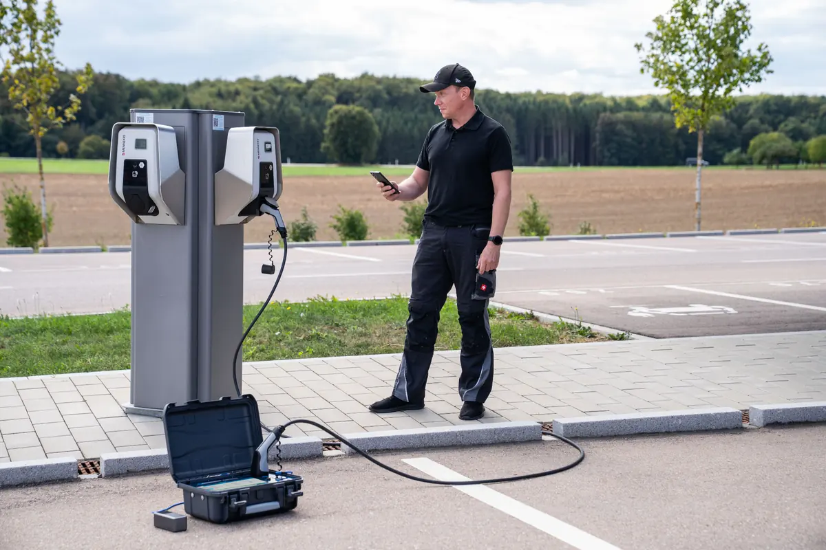 Easy Chester Micro connected to an AC charging point, with a technician standing beside it.