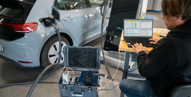EVCA Interop open case connected between a real electric vehicle and charging station while an engineer analyses the synchronized session