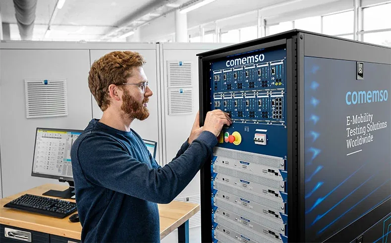 Ein comemso-Applikationsingenieur arbeitet im Labor an einem rackbasierten Battery Cell Simulator.