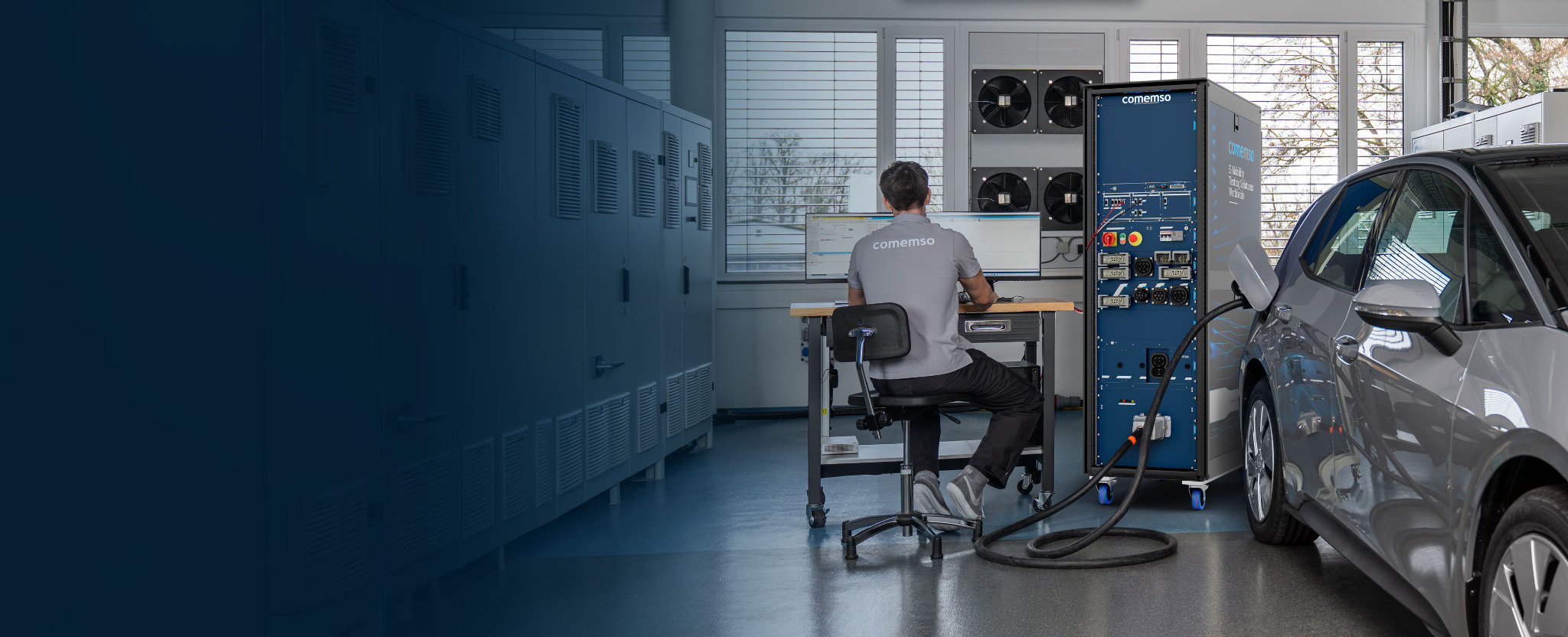 Electric vehicle connected to a comemso EV charging test system while an engineer evaluates the charging session in the laboratory