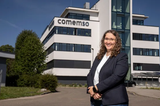 A comemso employee in front of the company building.