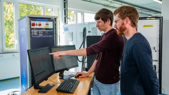 Two comemso employees working with an EVSE test setup in the laboratory.
