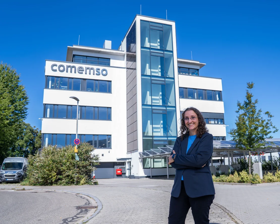 A comemso employee in front of the company building.